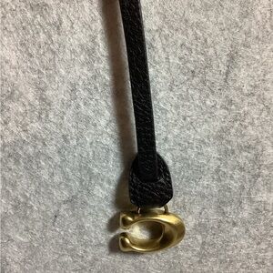 Black Leather strap with Gold 'C' Pendant. They C is a gold coach pendant.